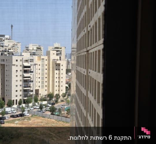 נוף עירוני עם בניינים גבוהים דרך רשת חלון